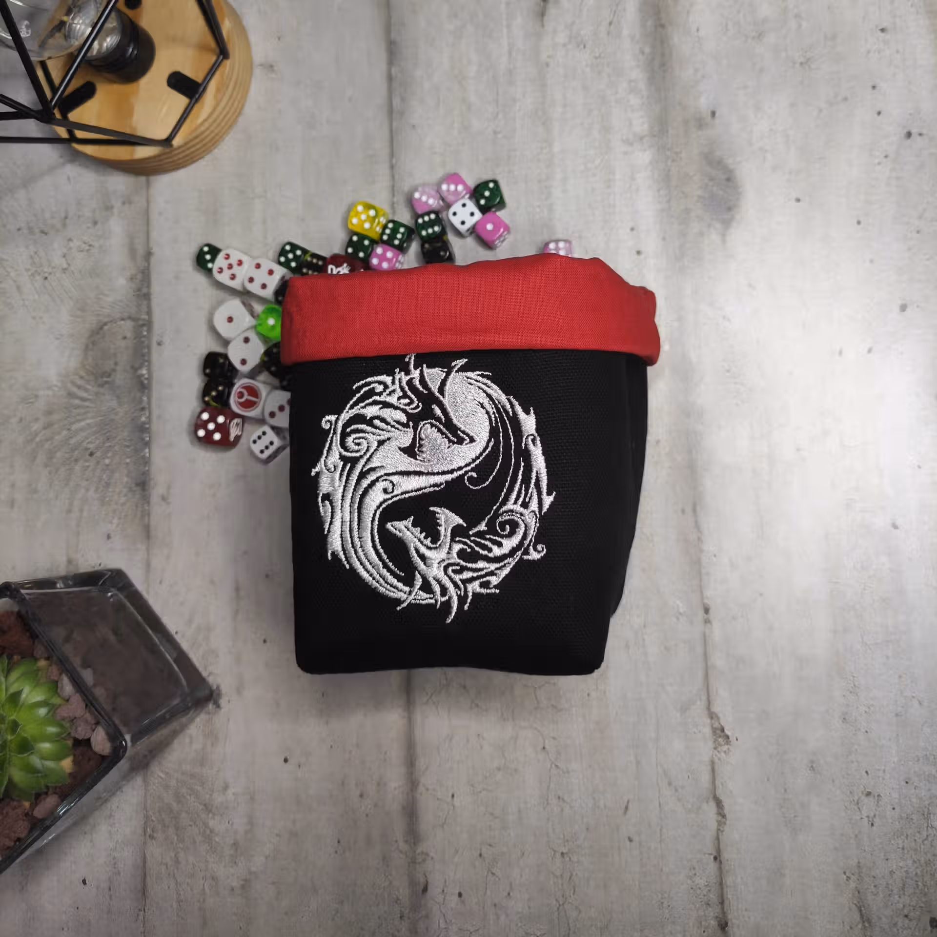 bourse à dé carrée brodée noire et rouge avec deux dragons blancs yin yang devant des dés