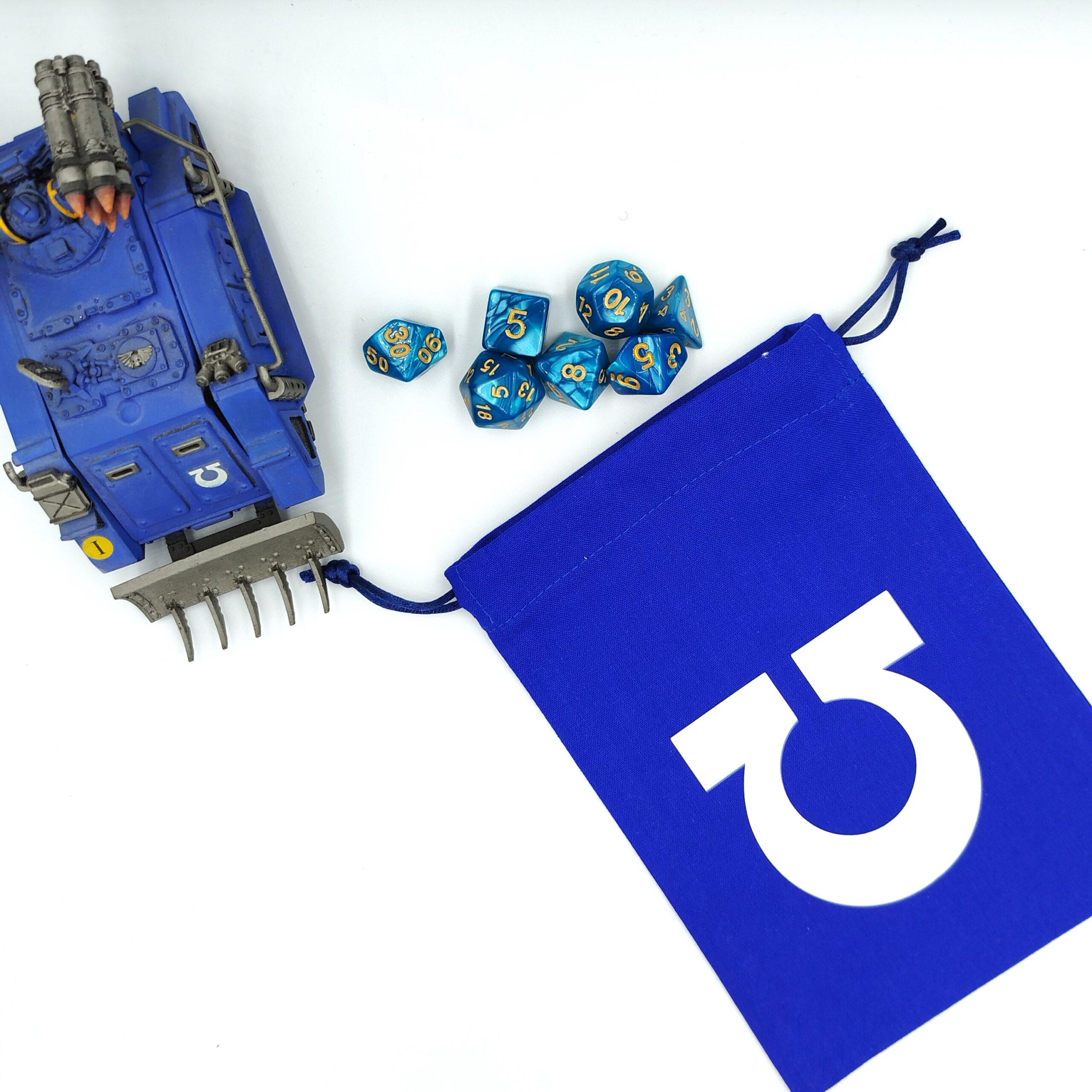 bourse à dés bleu avec le symbole oméga renversée devant un whirlwind ultramarine mk1 et des dés